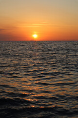 Obraz premium Seascape orange sunset and silhouette of Stromboli volcano in the haze on the horizon, Calabria, Italy