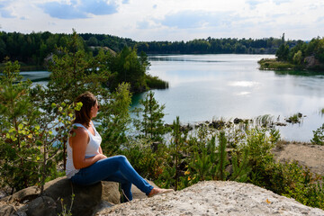 Naklejka na ściany i meble A man sits on the shores of a basalt lake, a tourist destination of Ukraine.