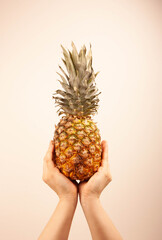 Woman holding a pineapple with both hands