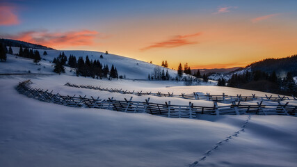 snowy landscape with snow barriers after sunset with animal footprints