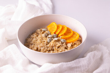 Oatmeal with tangerines and olive oil in a white plate. Horizontal orientation. Close up.
