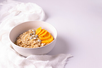 Oatmeal with tangerines and olive oil in a white plate. Horizontal orientation. Сору space.