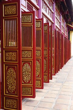 Series of ornate carved and painted wooden doors with gilded ornaments at a temple in Vietnam