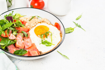 Savory breakfast. Oatmeal porrige with salted salmon, egg and fresh salad. Healthy food, balanced nutrition.