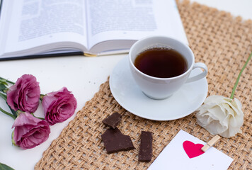 Magic mood atmosphere of love picture for post in Instagram. Take break, rest with tea and book, decorated by flowers and note, on table with brown napkin. Learning is development. Layout.