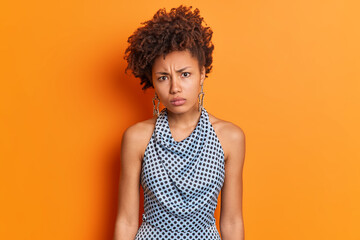 Portrait of displeased offended dark skinned woman looks with disappointed expression wears...