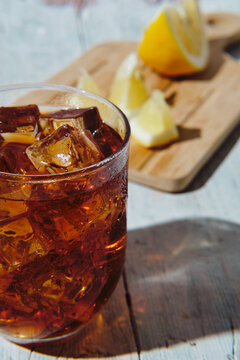 very cold cola on a white background with ice and lemon
