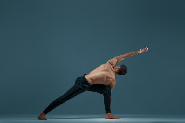 Male yoga doing stretching exercise in studio