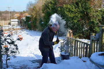 Senior man clearing snow off his decking .