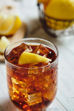 very cold cola on a white background with ice and lemon