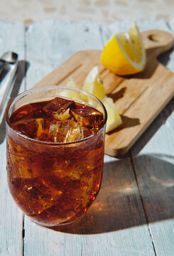 very cold cola on a white background with ice and lemon