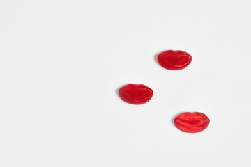 Three red gummy candy lips on white background