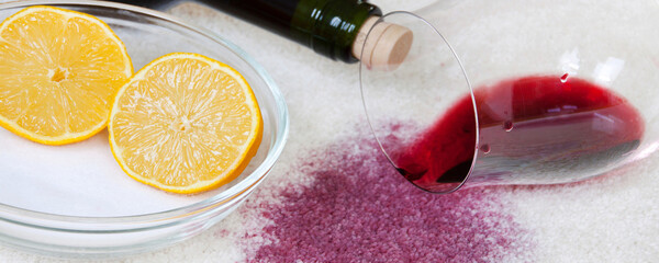 Umgestoßenes Weinglas mit Rotwein, Salz und Zitrone auf Teppich Haushaltsmittel Banner