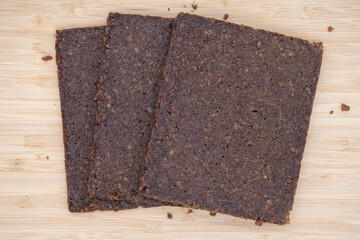 Three rectangular slices of pumpernickel bread on a wooden board