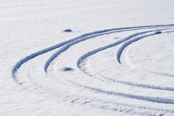 Fototapeta na wymiar Car tire tracks in the snow on a sunny day