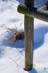 Wooden fence pole on a snow covered filed on a sunny day