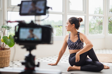 Asian woman trainer making online live streaming training and show how to exercise workout, yoga at home