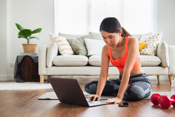 Sporty woman watching and learning exercises workout, yoga online with coach on screen of laptop computer at home