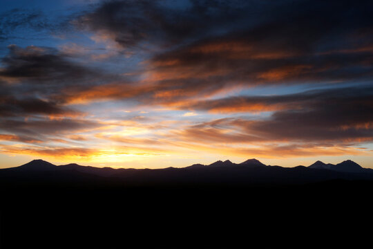 Scenic view of silhouette mountains against cloudy sky during sunset