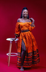 beautiful happy african woman in traditional dress posing on red background, studio shot
