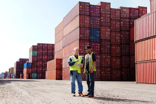 Workers using tablet computer while discussing at commercial dock