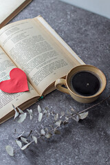 Naklejka na ściany i meble a cup of black coffee and a red paper heart on an open book