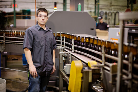 Portrait of man standing by bottling plant at brewery