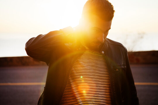 Handsome man walking on coastal road against sky during sunset - Powered by Adobe