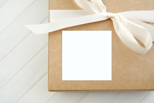 White Square Gift Sticker Mockup On Gift Box With White Ribbon, Adhesive Label For Design Presentation.