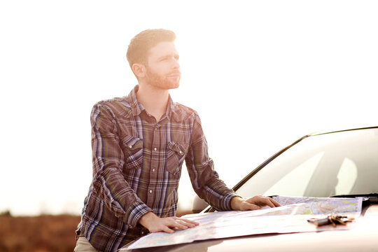 Man with map looking away while standing by car against clear sky