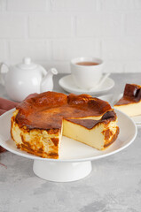 San Sebastian cheesecake on top on a white plate on a gray concrete background. Traditional Spanish dessert. Copy space