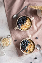 Flat lay of bowls with oatmeal porridge and blueberries