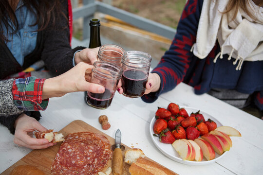 Cropped image of friends toasting wine glasses while having food at table