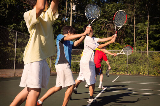 Players standing in row playing tennis against fence at court