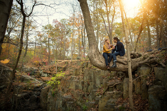 Couple sitting on tree trunk in forest