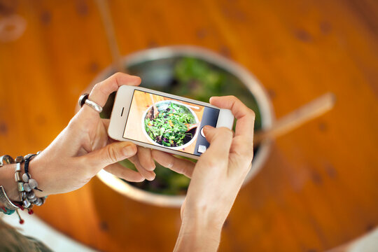 Cropped image of woman photographing salad in bowl