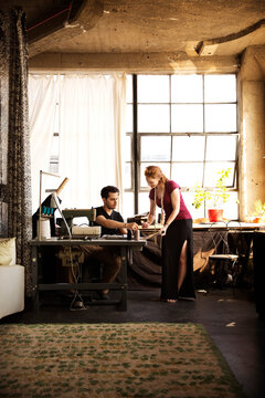 Fashion designers working with coworker against windows at workshop