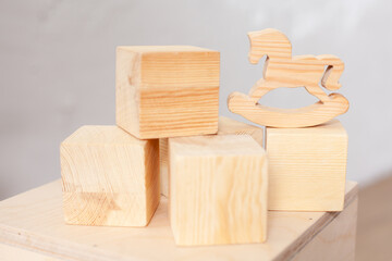 Wooden cubes and a horse for children's games. Child development. Security. Classes with a child. No plastic. Ecology and naturalness. Childhood. Close-up in natural tones.