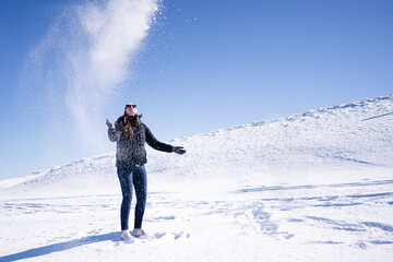 Handsome woman with sunglasses throwing snow in the air.