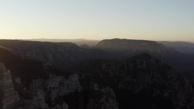 Aerial view of eroded rocks and a valley, in the highlands of Arizona, sunset - tracking, pan, drone shot