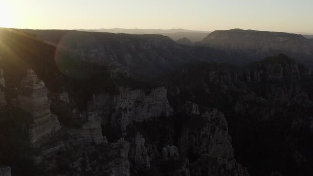 Aerial view of rock pillars, canyon and mountains, sunset, in Arizona - tracking, tilt drone shot