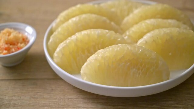 Fresh peeled pomelo, grapefruit or shaddock on white plate
