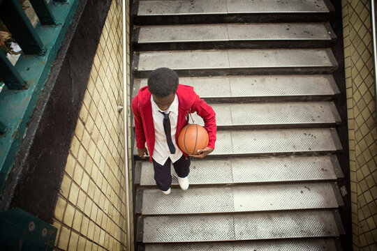High angle view of student holding basketball walking down steps