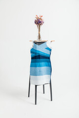 Luxury blue shirt dress hanging on wooden chair in studio.