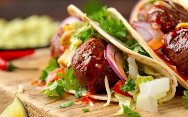 Meat free beetroot and pea protein meatballs taco wraps with avocado guacamole, sweet chilli sauce and lime wedges