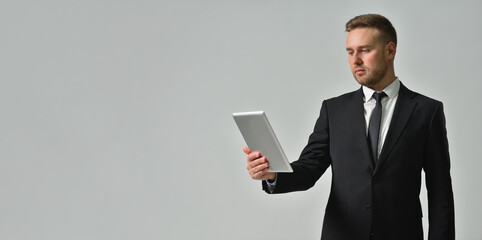 Business person looking attentively in digital tablet on gray background
