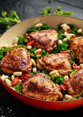 One-pot braised chicken thighs with kale and cannellini beans served with chili peppers