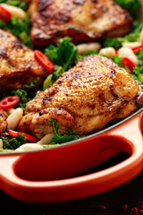 One-pot braised chicken thighs with kale and cannellini beans served with chili peppers
