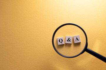 Magnifying glass focus on Q&A wooden alphabet letter. Concept of question and answer