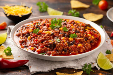 Chilli con Carne with tortilla chips and cheese in white bowl. Mexican food.